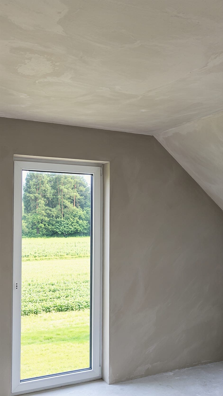 Glatt verputztes Dachzimmer mit Dachschräge und hohem Fenster
