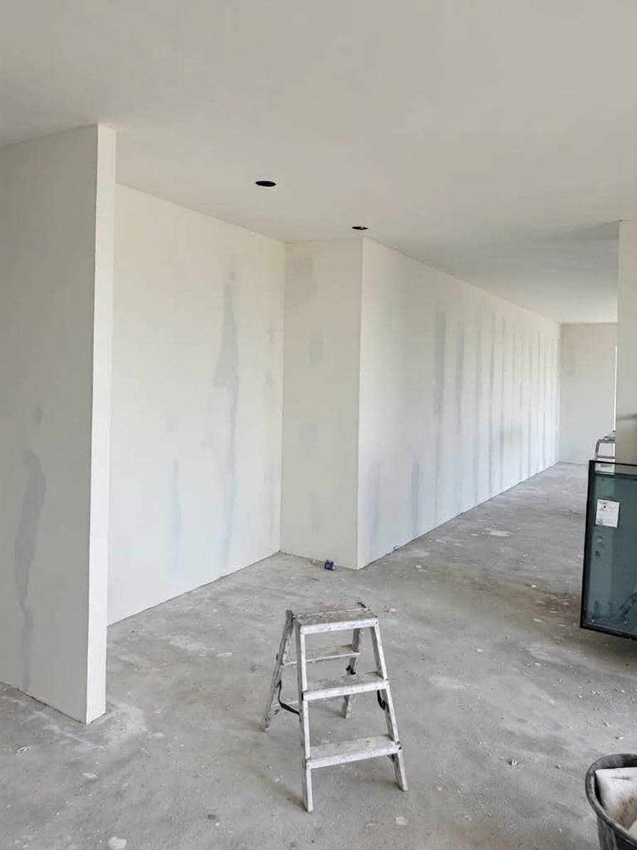 Lange Wand im Wohnbereich mit verspachtelten Fugen, Trittleiter auf dem Betonboden