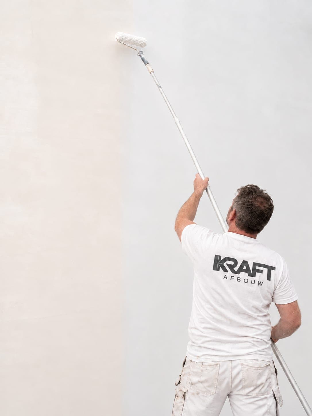 Painter rolling a wall with an extension roller