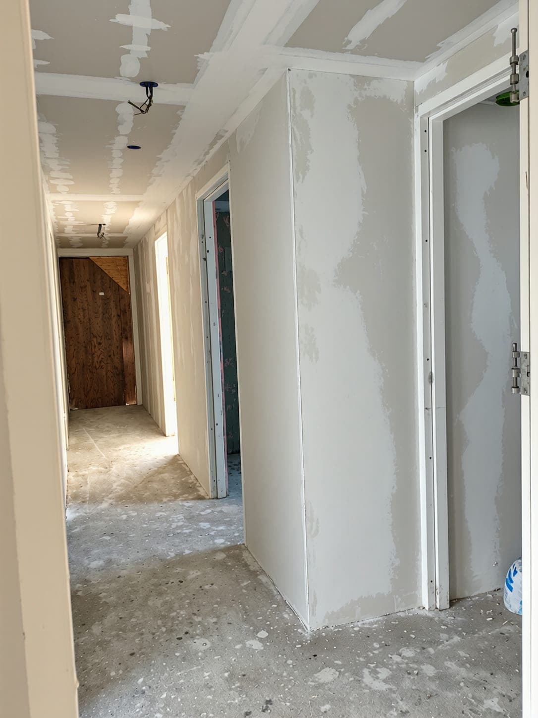 Dezelfde hal voor het stucwerk: gipswanden en plafond met gevulde naden, kale vloer