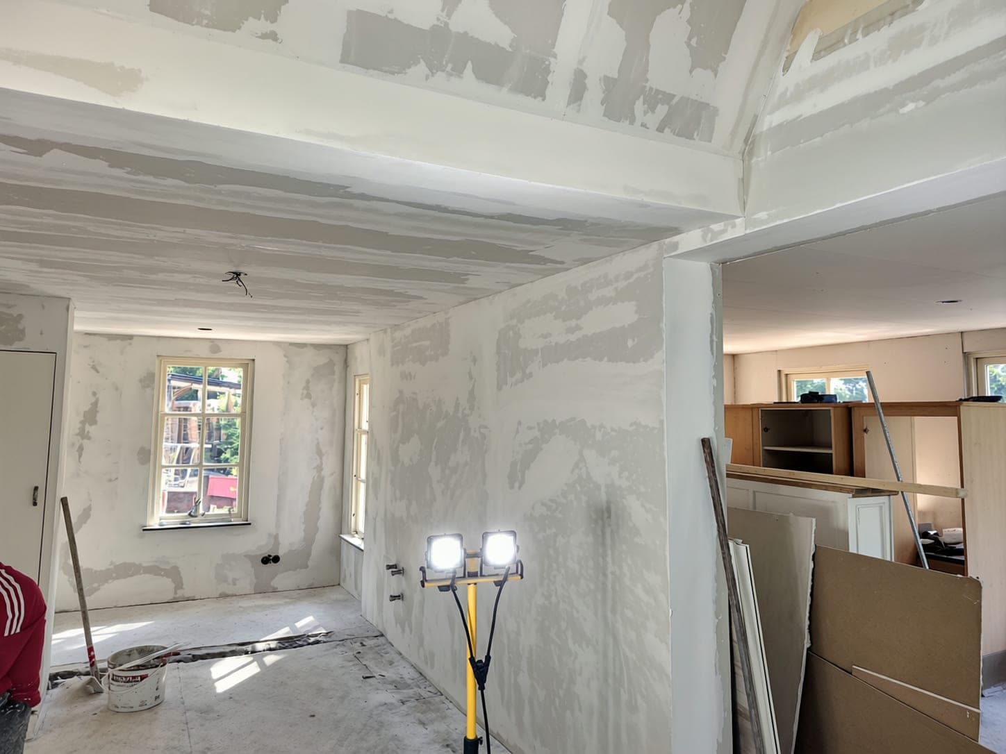 Woonkamer met wanden en plafond in bewerking, doorkijk naar de keuken
