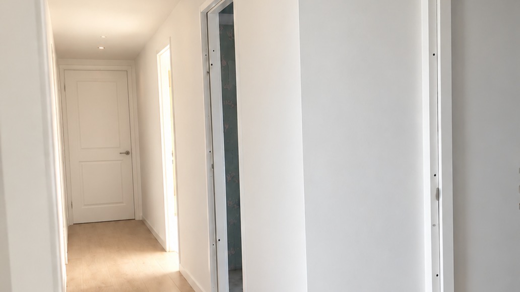Opgeleverde hal met glad gestucte wanden en plafond en een deur aan het einde